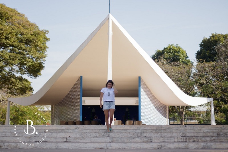 Mulher de blusa branca na frente da igrejinha de Brasília.